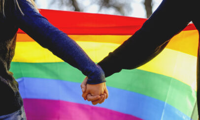 Two girls holding hands and a rainbow flag